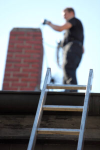 chimney sweep on roof next to red brick chimney - Elkton MD - Ace Chimney Sweeps